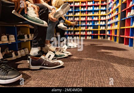 Des amis qui essaient des chaussures de bowling à Alley Banque D'Images