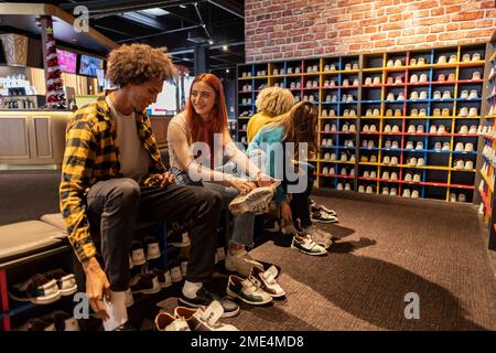 Amis multiraciaux essayant des chaussures à la piste de bowling Banque D'Images