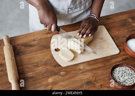 Vue de dessus de la femme noire qui cuit la pâtisserie maison sur le comptoir de cuisine en bois sombre, espace de copie Banque D'Images