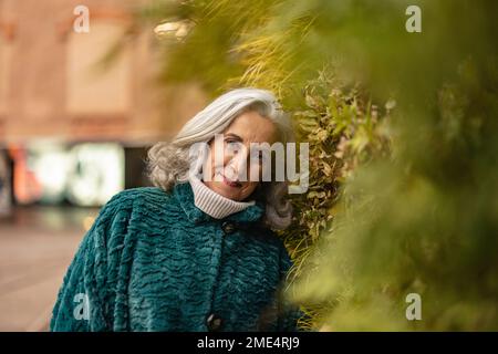 Femme aînée souriante penchée sur les plantes Banque D'Images