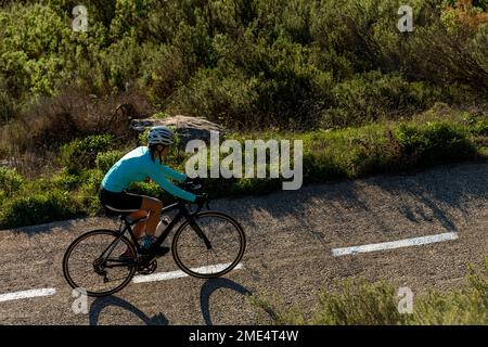 Cycliste en vélo sur la route par les plantes Banque D'Images