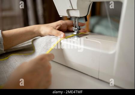 Mains de la femme à coudre le tissu à l'aide d'une machine à coudre Banque D'Images