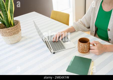 Travailleur indépendant utilisant un ordinateur portable avec une tasse de thé sur le bureau à la maison Banque D'Images