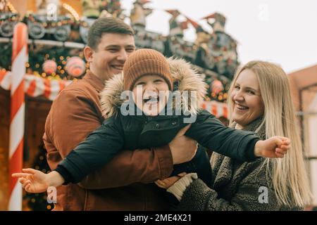 Père heureux et mère s'amusant avec son au marché de Noël Banque D'Images