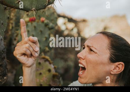 Femme criant dans la douleur et touchant la plante de cactus Banque D'Images