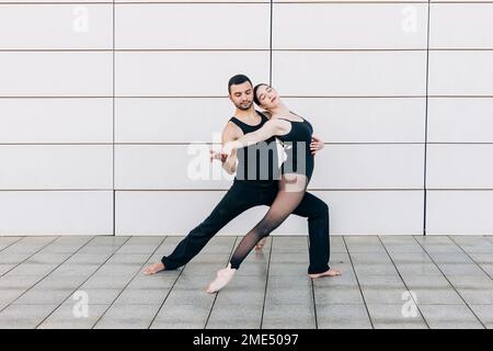 Couple avec les yeux fermés en train de danser devant le mur Banque D'Images