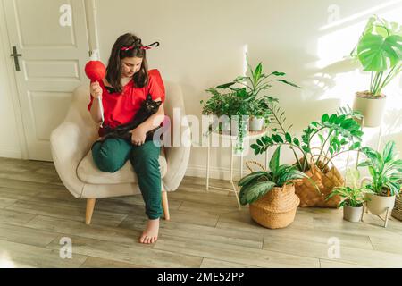 Fille en costume de insecte assise avec chat à la maison Banque D'Images