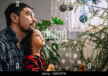 Père et fils regardant l'arbre de Noël décoré Banque D'Images