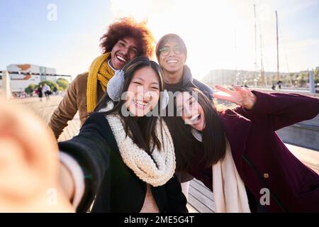 Groupe d'amis joyeux prenant un selfie à l'extérieur de la ville, souriant et regardant l'appareil photo. Banque D'Images