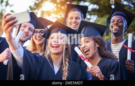 C'est le plus grand jour de notre vie jusqu'à présent. un groupe d'étudiants de l'université prenant un selfie le jour de la remise des diplômes. Banque D'Images