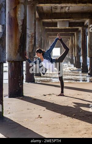 Une femme pratiquant le yoga à l'extérieur, faisant la posture debout de l'arc Banque D'Images