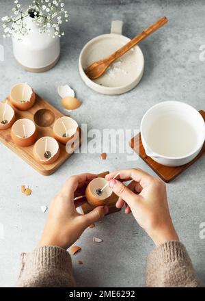 Étape 2. La fille a inséré la longueur de la mèche au centre de la coquille d'œuf. Concept d'artisanat naturel pour enfants. Fabrication de bougies à la mode pour Pâques. Banque D'Images