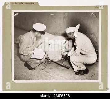 La Garde côtière aide les blessés. Dans un port nord-africain, un soldat américain blessé donne des informations au gardien de la côte Earl Sauter (à gauche), le compagnon du pharmacien en chef de Milwaukee, Wisconsin, après avoir été transféré des plages italiennes à bord d'un transport d'assaut assuré par la Garde côtière. Frank Shea (à droite), pharmacien's Mate second Class, U.S.N. de Rockaway Beach, long Island, New York, aide. Le soldat a été blessé sur les plages d'Italie. Banque D'Images