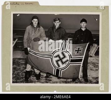 La swastika est ramenée vers le bas alors que la garde côtière marque Knockout. Cette image représente trois petits officiers en chef de la Garde côtière exposant le drapeau de bataille allemand qui a autrefois décollé du mât d'un navire de guerre allemand. Banque D'Images