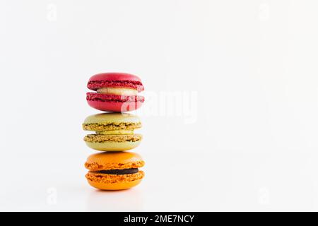 Pile de biscuits au velours rouge, au pistache et au chocolat et au macaron mandarin sur fond blanc Banque D'Images