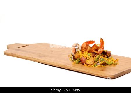 Riz à la paella servi sur une planche de bois avec un saupoudreuse de sel et des fourchettes préparées avec des fruits de mer, des marrons, du safran, des saucisses et de la viande. Plat traditionnel de Valenci Banque D'Images