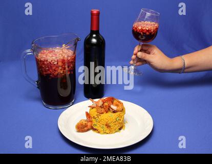 Riz à la paella préparé avec des crevettes, du safran, du poulet, des fruits de mer et des légumes, plat traditionnel de Valence Espagne accompagné d'un pichet de cléricate Banque D'Images