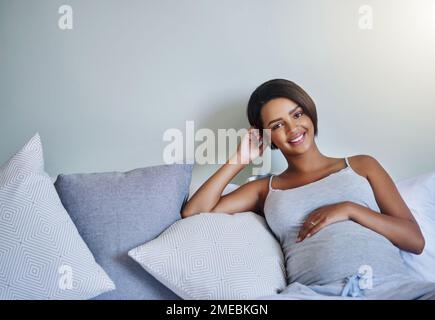 C'est facile avant que mon tout-petit arrive. une jeune femme enceinte se relaxant sur le lit à la maison. Banque D'Images