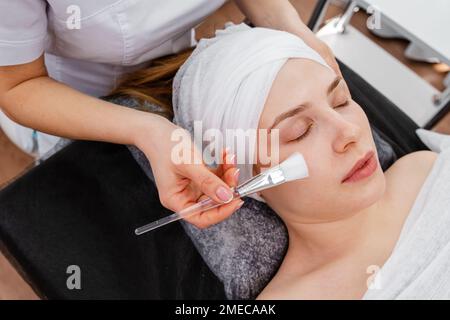 Esthéticienne travaillant avec femme client. Femme se peeling du visage Banque D'Images