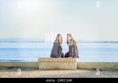 Les meilleurs sièges de la maison. Portrait arrière de deux jeunes femmes attrayantes passant une journée au bord de l'océan. Banque D'Images
