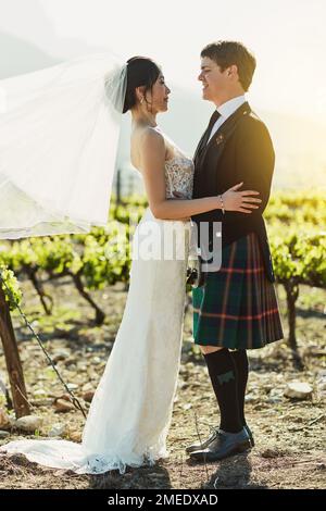 Ils font un couple étonnant. une jeune mariée et marié joyeux se tenant les uns les autres tout en regardant l'oeil à l'extérieur pendant la journée. Banque D'Images