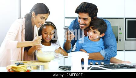 Immortalisez nos souvenirs culinaires. une jeune famille fait des crêpes ensemble dans la cuisine à la maison. Banque D'Images