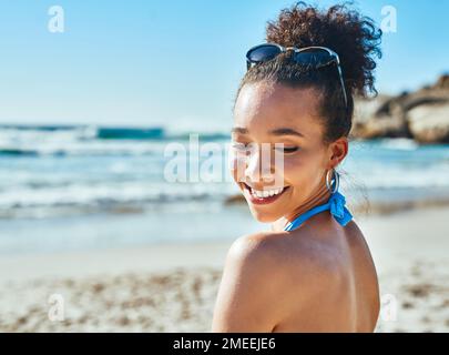 Le moyen le plus sûr de briller. une belle jeune femme qui profite d'une journée d'été à la plage. Banque D'Images