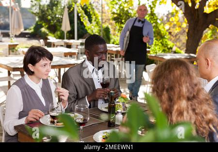 De bons amis boire du vin rouge dans un café d'été Banque D'Images