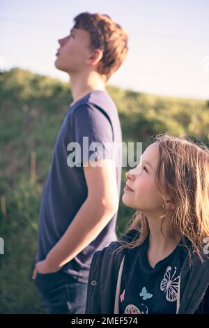 Détail du visage de la jeune fille à partir du profil, en regardant devant elle, son frère étant visible derrière elle en regardant dans la même direction. Thoughful, affectueux, pr Banque D'Images