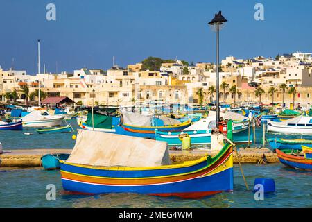 Marsaxlokk, Malte - des bateaux de pêche traditionnels colorés de Luzzu au marché de Marsaxlokk avec eau de mer turquoise et ciel bleu clair lors d'une belle journée d'été Banque D'Images