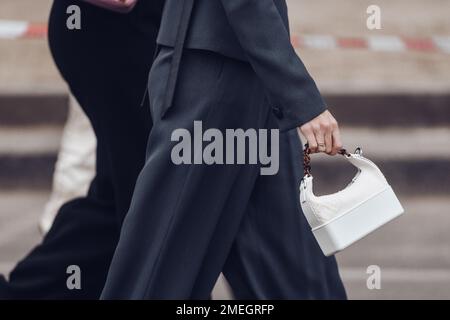 Milan, Italie - 24 février 2022: Rogner une femme méconnaissable en costume noir avec sac à main blanc. Banque D'Images