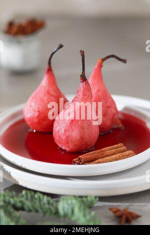 Assiette de poires pochées sucrées au vin rouge sur fond clair. Banque D'Images