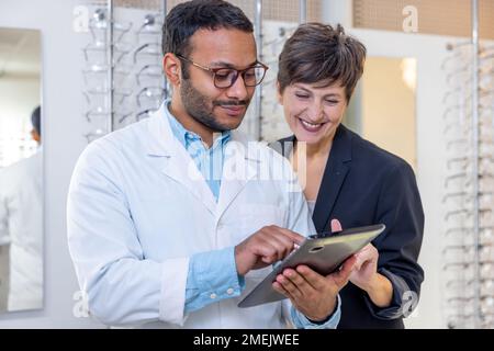 Optométriste masculin aidant une femme à choisir des lunettes Banque D'Images