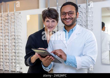 Optométriste masculin aidant une femme à choisir des lunettes Banque D'Images
