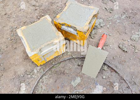 Deux moules cubes pleins de béton, échantillons pour les essais de traction ou de flexion et essai de résistance à la compression du mélange de ciment de construction pour Banque D'Images