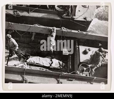 Coast Guardsman tué en France invasion prise à bord du Battleship. Un américain mort Coast Guardsman, Coxswain d'un LCVP, est pris à bord d'un américain Cuirassé avec des Rangers américains et capturé des prisonniers allemands et italiens. Le garde-côtes a été abattu par un Sniper nazi lorsque son embarcation débarratait des troupes sur la côte française. Banque D'Images