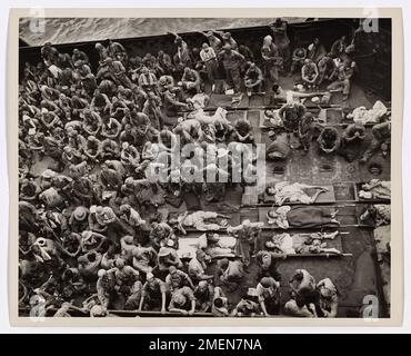 Photographie de 221 prisonniers de guerre japonais à bord de l'embarcation. Prisonniers de guerre du JAP transférés au transport de troupes de garde côtière. Une autre indication que tous les Japonais ne se battent pas à la mort est ce sac de 221 prisonniers de guerre Nip. Entorrés sur le pont d'un LCT (Landing Craft, Tank), ils sont amenés à un transport de troupes de la Garde côtière à Guam pour le transfert à Pearl Harbor. Trente des prisonniers ont été pris à Guam, tandis que le solde a été capturé à Iwo Jima. Certains blessés reposent sur des brancards. Pour la plupart, les prisonniers étaient minces, ce qui indique que même leur régime habituel o Banque D'Images