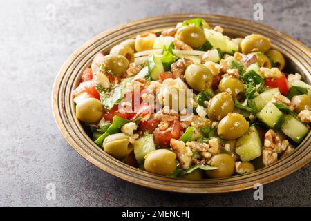 Salade d'olives vertes turques aux noix, tomates, concombres, persil dans une assiette sur la table. Horizontale Banque D'Images
