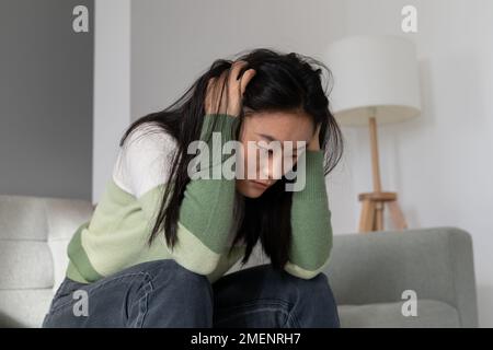 Inquiète anxieuse fille asiatique millénaire tenant la tête dans les mains face à la dépression après l'avortement Banque D'Images