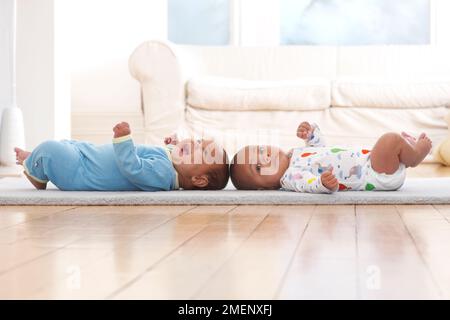 Deux bébés garçons allongé sur le dos sur un tapis, 4 mois Banque D'Images