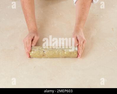 Fabrication de biscuits de Stilton et de noix, pâte de refroidissement enveloppée dans un film de clingfilm Banque D'Images