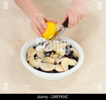 Bleuet Cobbler, mettre les ingrédients dans le plat et ajouter le zeste de citron râpé Banque D'Images