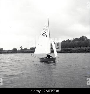 1960s, historique, un garçon naviguant sur un canot pneumatique le long des Norfolk Broads, Angleterre, Royaume-Uni. Banque D'Images