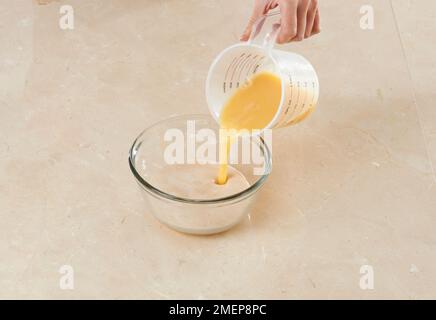 Fabrication de Brioche des rois, en ajoutant des œufs à la levure, à l'eau chaude et au mélange de sucre Banque D'Images