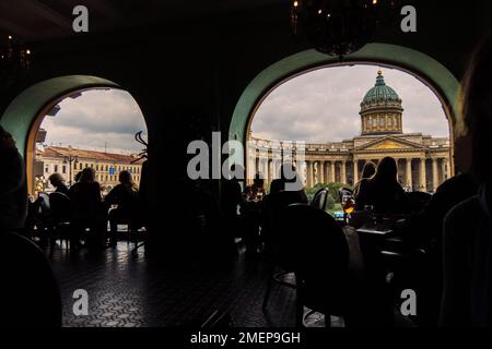 Vue sur la cathédrale de Kazan depuis le café Singer par la fenêtre. Silhouettes de personnes assises à des tables dans l'ancienne maison de la chanteuse à Saint-Pétersbourg, Russie. Photo de haute qualité Banque D'Images