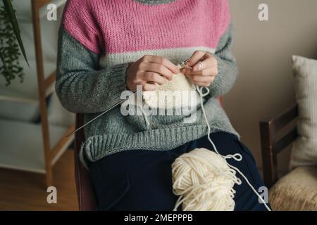 Gros plan sur les mains d'une femme douillette femme en tricot chaud tricoté aime le travail en tricot sur une chaise à la maison en hiver confortable. Nouveau petit Banque D'Images