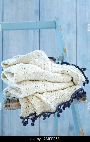 Plaid en forme de vague et de coquille blanc avec bord bleu, sur chaise en bois Banque D'Images