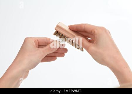 À l'aide d'une brosse en laiton doux pour appliquer le fini satiné sur l'argile métallique cuite, gros plan Banque D'Images