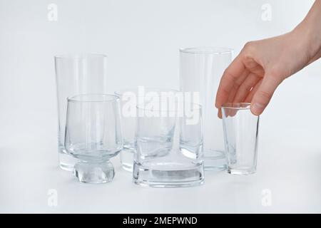 Variété de verres à boire avec femme ramasser de petits verres Banque D'Images