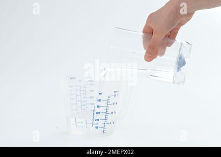 Femme versant de l'eau dans un verre gradué, gros plan Banque D'Images